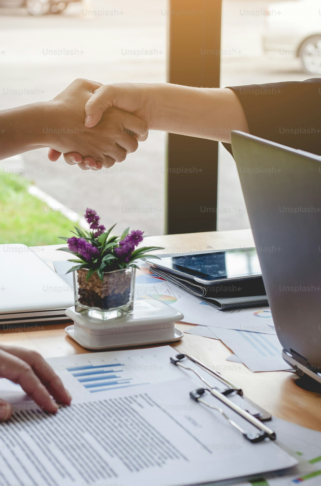 Professional handshake over a workspace desk